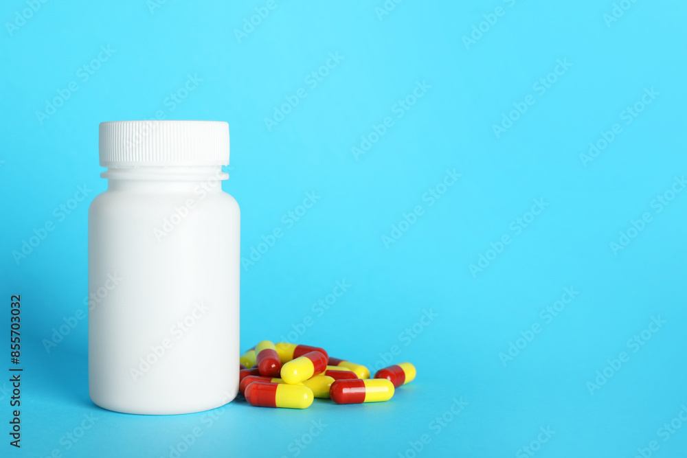 Antibiotic pills and bottle on light blue background, space for text. Medicinal treatment Antibiotic pills and bottle on light blue background, space for text. Medicinal treatment