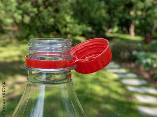Slika na platnu Close-up of the red plastic bottle cap attached to the bottle with extra strip o