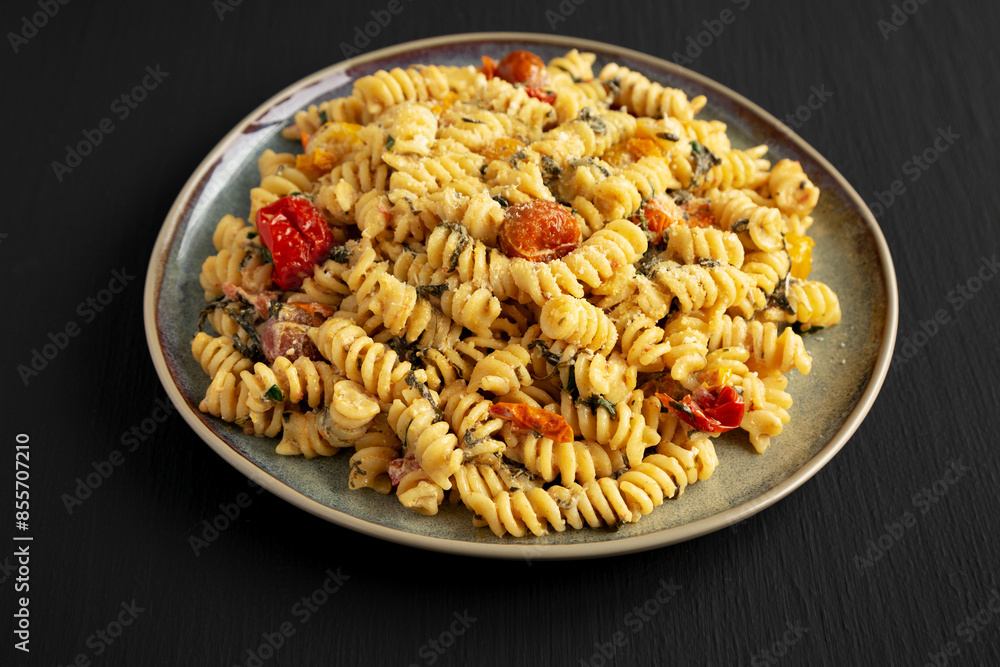 Homemade Baked Boursin Pasta on a Plate on a black background, side view. Homemade Baked Boursin Pasta on a Plate on a black background, side view.