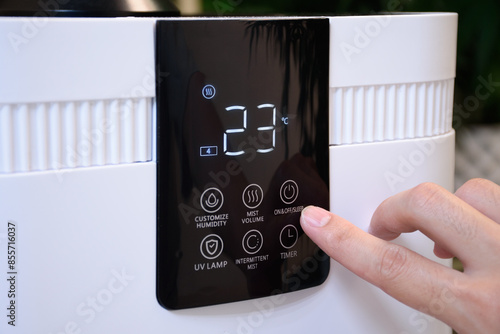 Close up of hand pressing button on thermostat or air conditioner in smart farm or modern home. Temperature regulator or air conditioner cooling and fingers pressing buttons in a hydroponic farm.