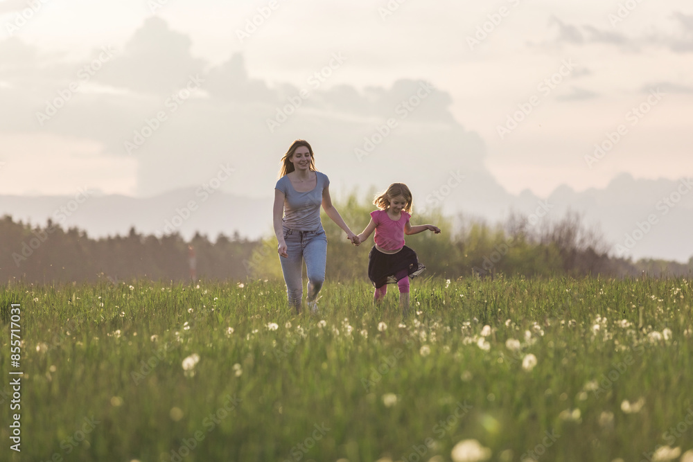 Mother and her little daughter running holding hands in the beautiful nature towards the setting sun. Mother and her little daughter running holding hands in the beautiful nature towards the setting sun.