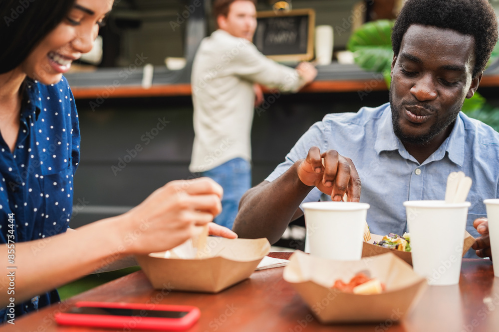 Fototapeta premium Multiracial people having fun eating at food truck restaurant outdoor - Summer lifestyle concept - Focus on african american man face
