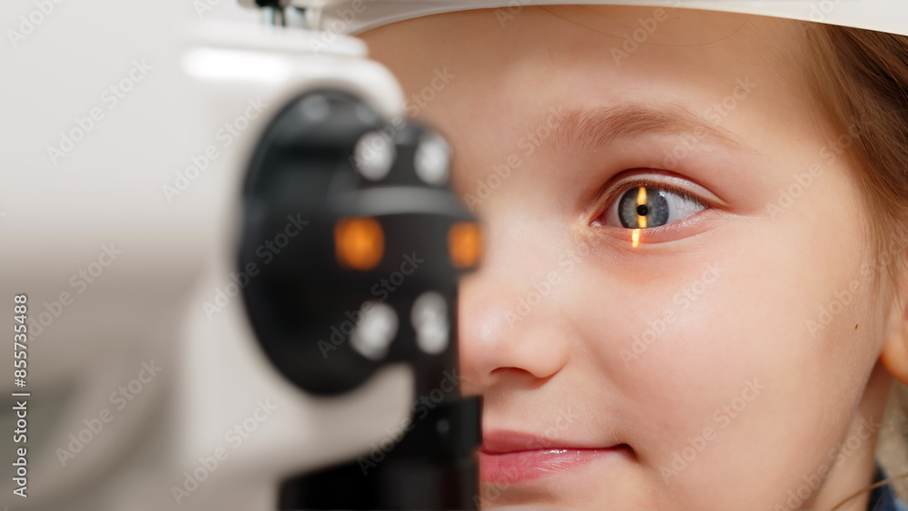 A little patient undergoes an eye test by a professional optometrist using modern diagnostic equipment in an ophthalmology clinic. A little patient undergoes an eye test by a professional optometrist using modern diagnostic equipment in an ophthalmology clinic.