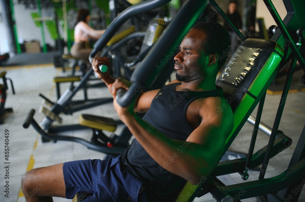 Fototapeta premium Athletic young black man having workout on chest press machine in gym