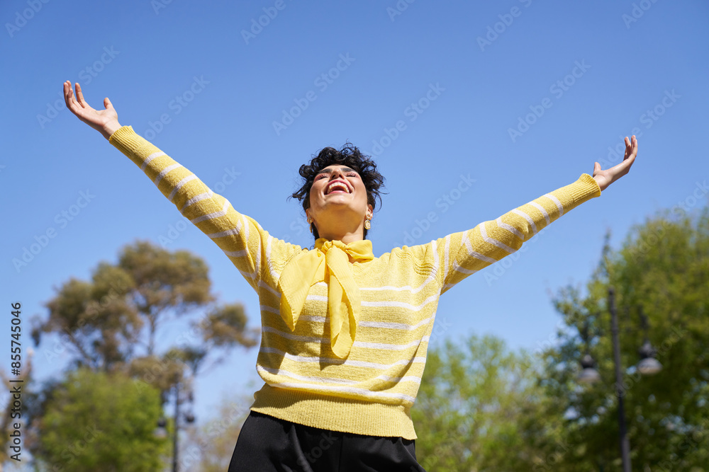 A woman in a yellow sweater is smiling and raising her arms in the air A woman in a yellow sweater is smiling and raising her arms in the air