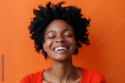 Portrait of a content afro-american woman in her 30s laughing over solid color backdrop © CogniLens