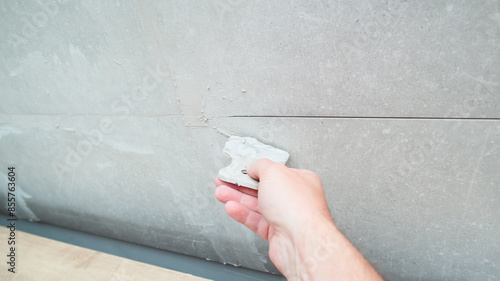 Grouting ceramic tiles using a fugue. Worker putting fugue on tiles closeup