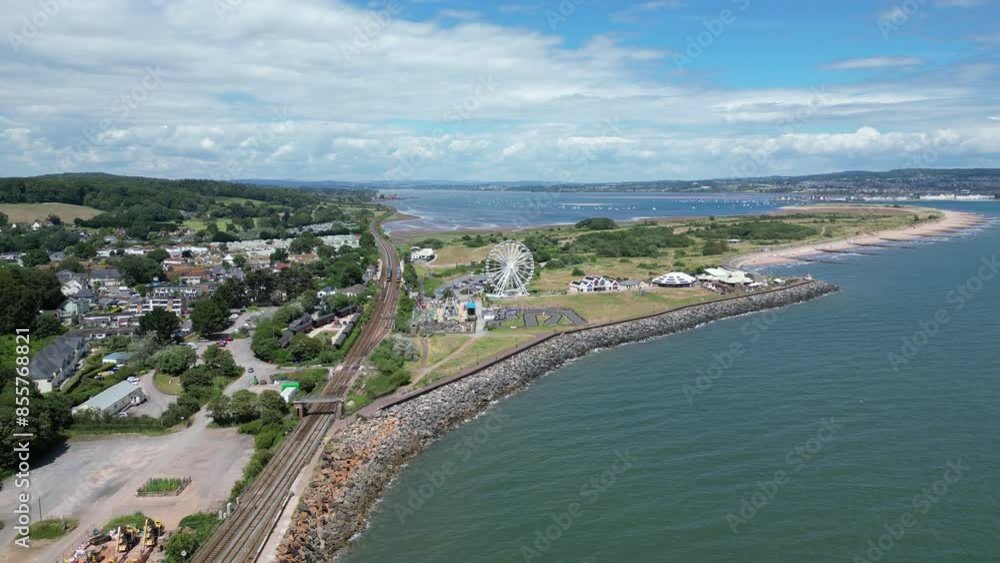 Dawlish Warren, River Exe, South Devon, England: DRONE VIEWS: The mainline railway; a ferris wheel on the Warren; the River Exe estuary in the background. South Devon is a popular UK holiday resort. Dawlish Warren, River Exe, South Devon, England: DRONE VIEWS: The mainline railway; a ferris wheel on the Warren; the River Exe estuary in the background. South Devon is a popular UK holiday resort.