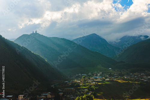 Beautiful view of Gergeti Trinity Church and kazbegi city with sun light, photo