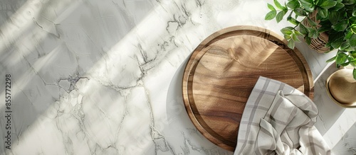 Wood cutting board with linen napkin and plant on marble table with copy space, top view. Copy space image. Place for adding text or design