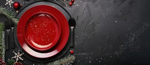 Top view of black Christmas table with red plate and white star shaped bowl, cutlery, fir branches and empty space for own text. with copy space image. Place for adding text or design photo
