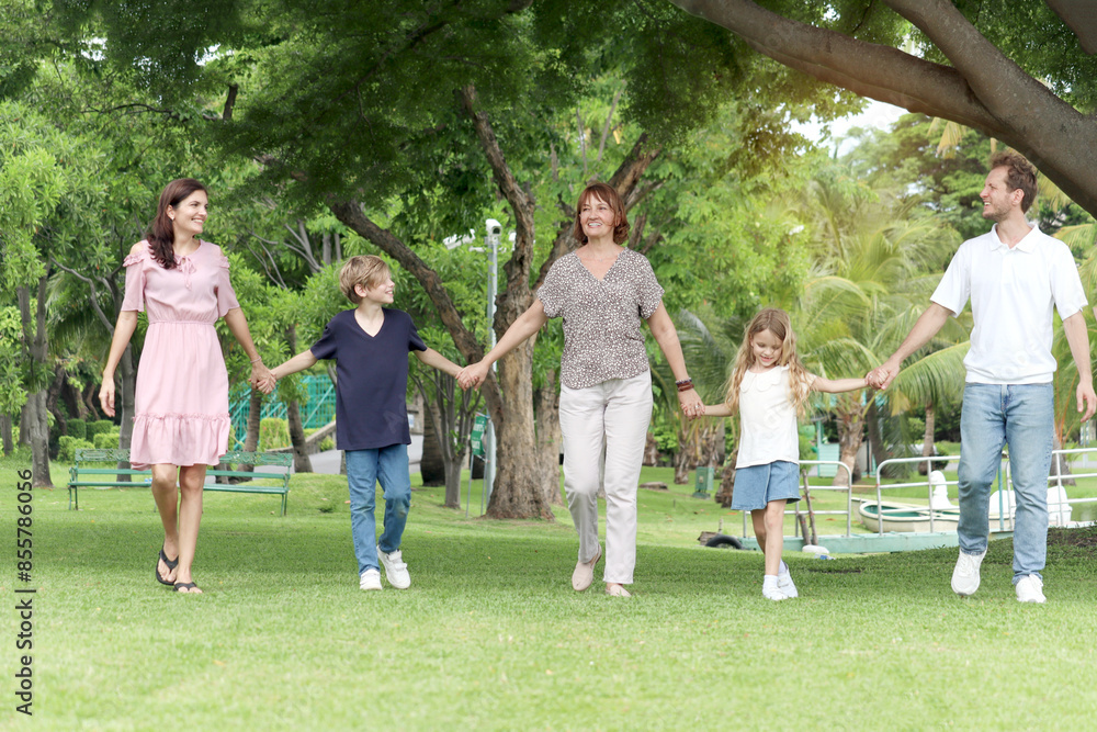Happy cheerful family hold hands, walk in line together outside. Father, mother, daughter girl, son boy and elderly grandma take a walk in summer garden. Joyful kid, parents and senior at green park. Happy cheerful family hold hands, walk in line together outside. Father, mother, daughter girl, son boy and elderly grandma take a walk in summer garden. Joyful kid, parents and senior at green park.