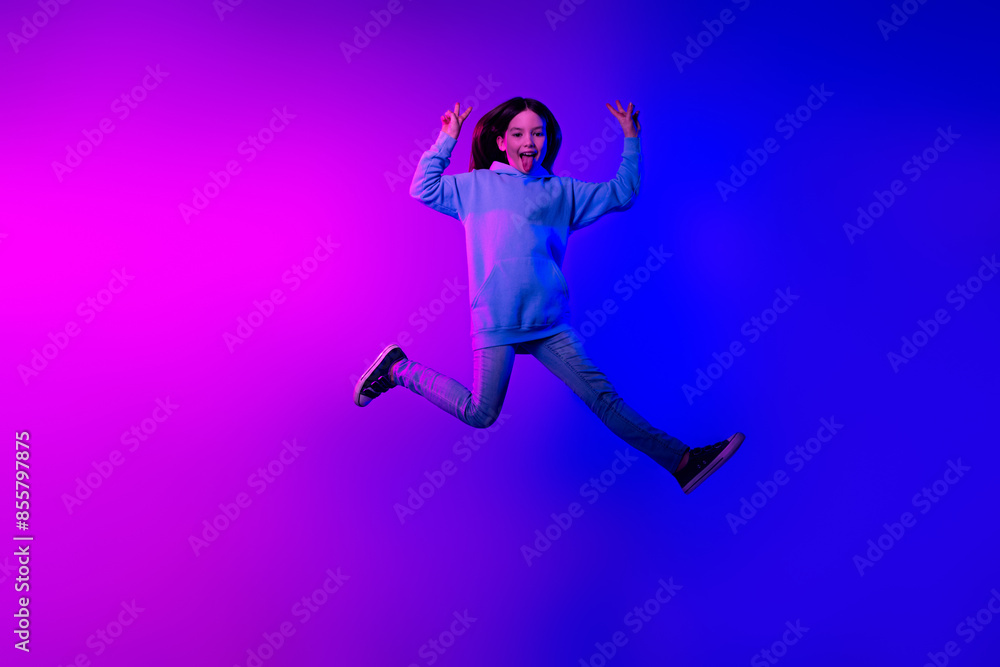 Full length photo of shiny attractive little lady dressed hoodie jumping high showing v-signs isolated neon pink color background Full length photo of shiny attractive little lady dressed hoodie jumping high showing v-signs isolated neon pink color background