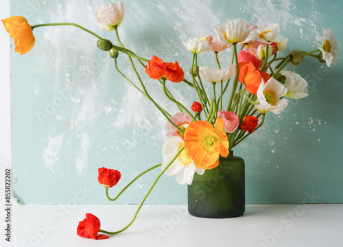 Quadro su tela green vase with a mono bouquet of multi-colored poppies on a blue background