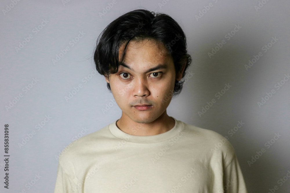 Portrait of an Asian Indonesian young man wearing a white shirt with a random expression when photographed with an isolated white background Portrait of an Asian Indonesian young man wearing a white shirt with a random expression when photographed with an isolated white background