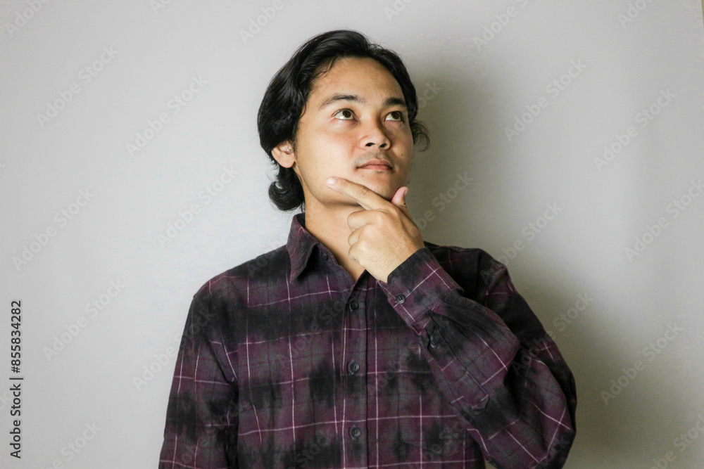 Portrait of an Asian Indonesian young man wearing a purple shirt with a random expression when photographed with an isolated white background Portrait of an Asian Indonesian young man wearing a purple shirt with a random expression when photographed with an isolated white background