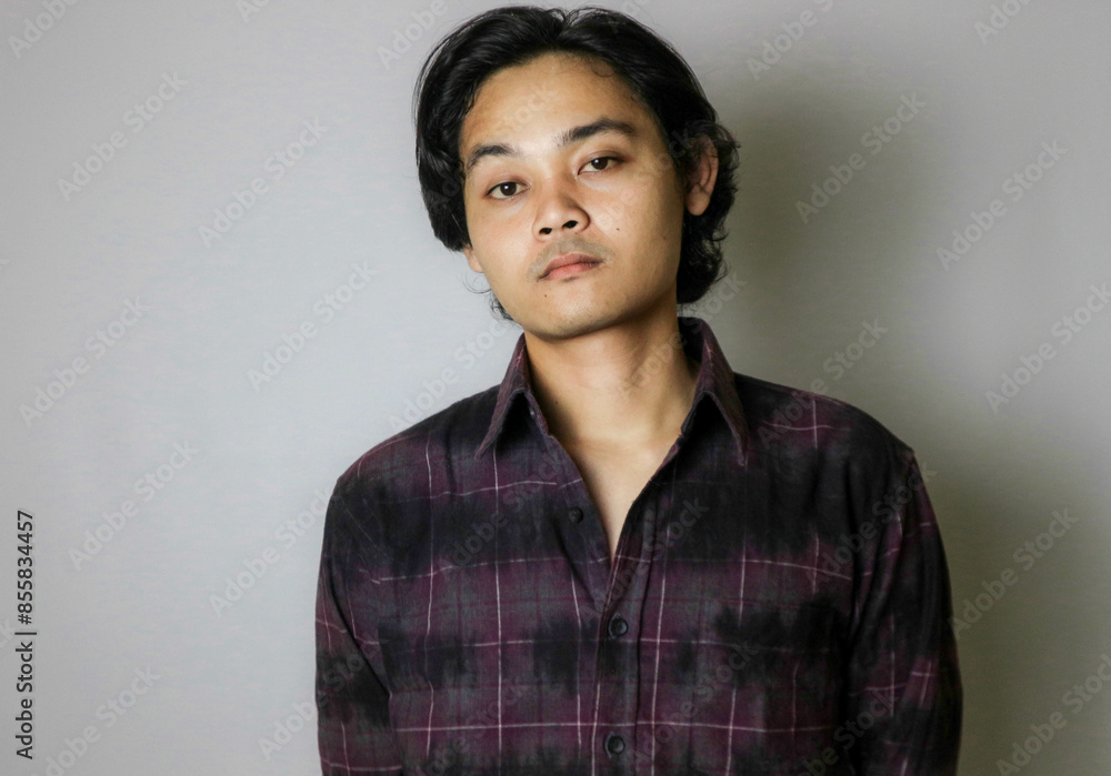 Portrait of an Asian Indonesian young man wearing a purple shirt with a random expression when photographed with an isolated white background Portrait of an Asian Indonesian young man wearing a purple shirt with a random expression when photographed with an isolated white background