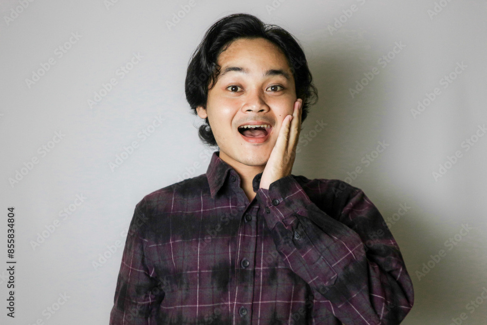 Portrait of an Asian Indonesian young man wearing a purple shirt with a random expression when photographed with an isolated white background Portrait of an Asian Indonesian young man wearing a purple shirt with a random expression when photographed with an isolated white background