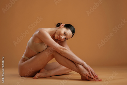 Sitting and resting on the floor. Woman with slim body shape is posing against background photo