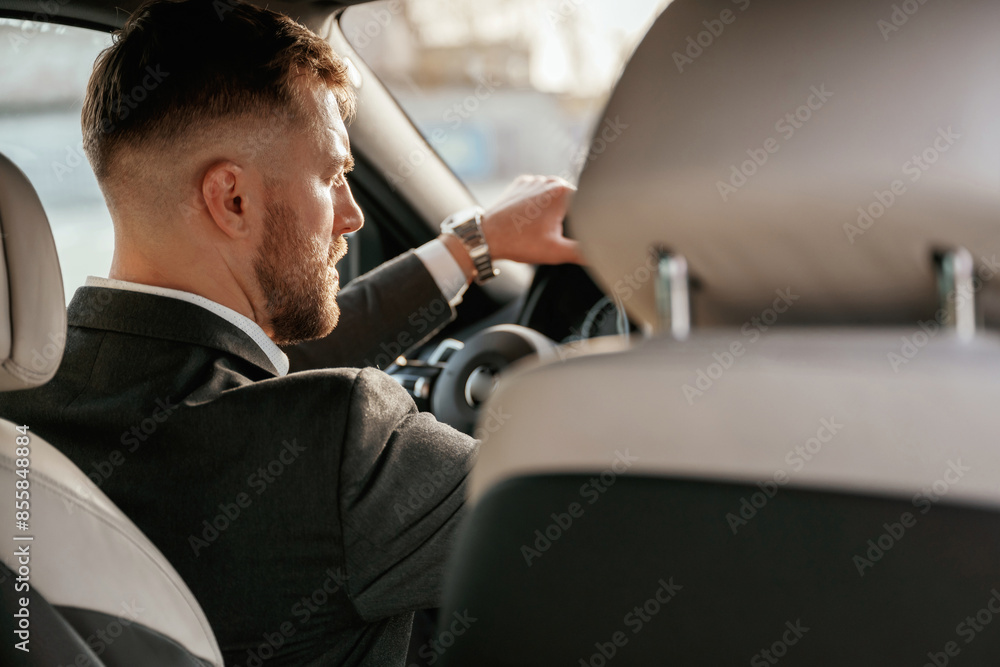 Driving, focused. Man in black suit is sitting in the car, driving Driving, focused. Man in black suit is sitting in the car, driving
