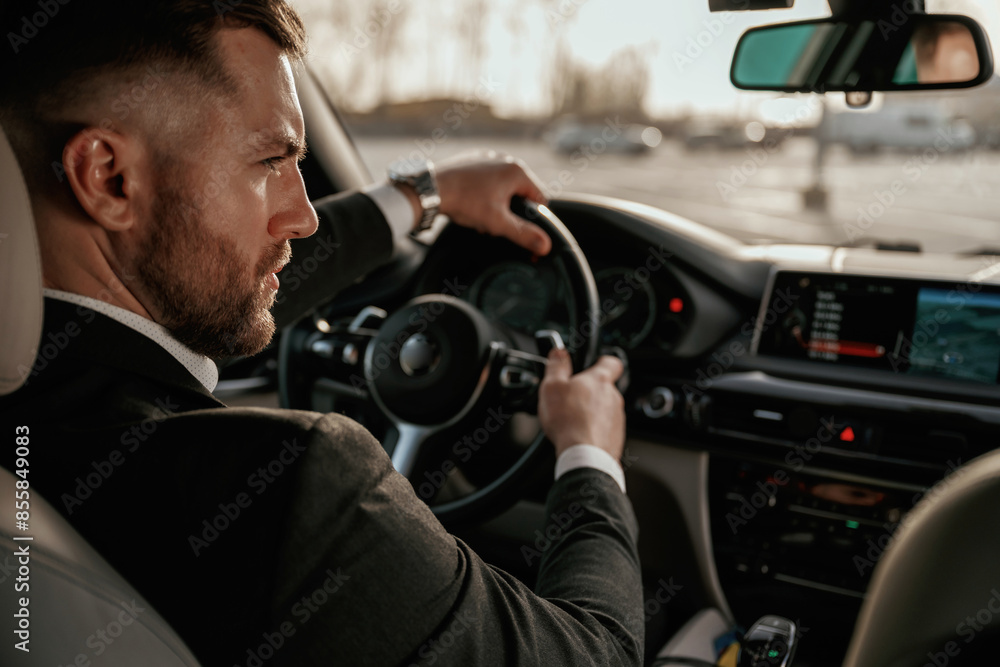 Driving, focused. Man in black suit is sitting in the car, driving Driving, focused. Man in black suit is sitting in the car, driving