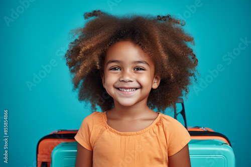 Cheerful African American girl ready for vacation, carrying a suitcase.