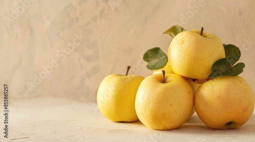 Selective focus image of golden delicious apples on a light beige backdrop with room for text