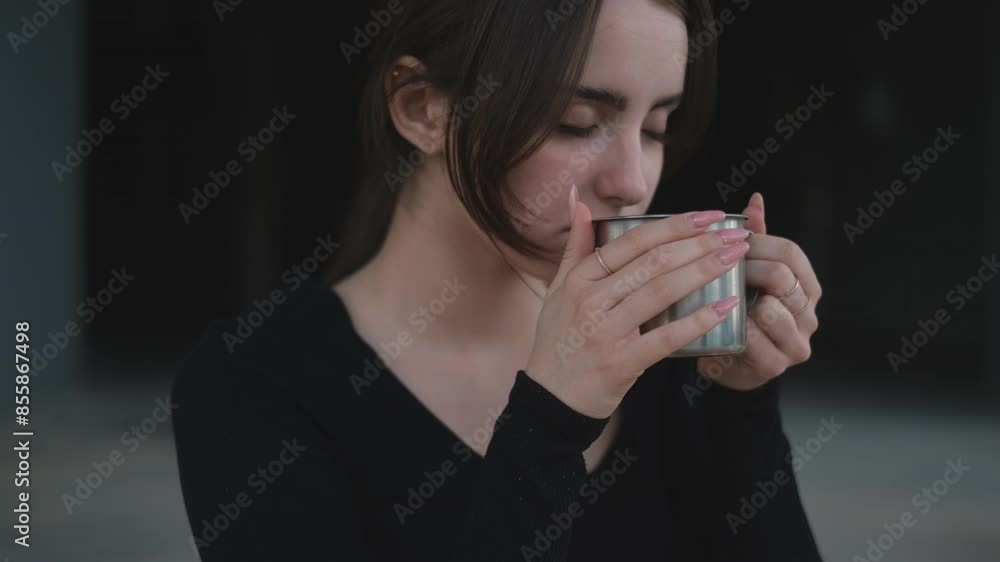 Young woman after yoga class drinks tea from a thermos on a yoga mat Young woman after yoga class drinks tea from a thermos on a yoga mat
