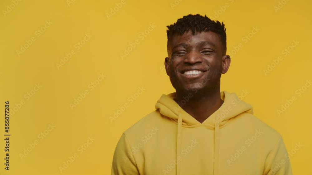 Smiling Man in Yellow Hoodie Against Yellow Background Smiling Man in Yellow Hoodie Against Yellow Background