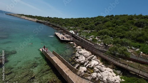 Wallpaper Mural lively beach scene in Turkey with vacationers enjoying the clear turquoise waters and rocky coastline. Wooden walkways provide easy access to the water, perfect for relaxation and fun in the sun Torontodigital.ca