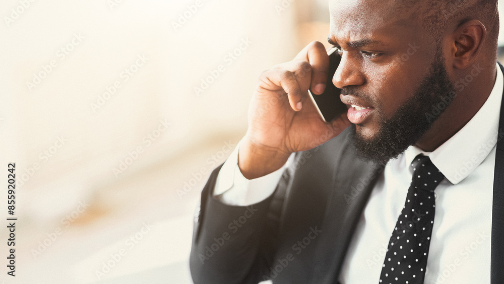 Got bad news. Close up of angry african businessman talking by phone with partners, panorama with copy space Got bad news. Close up of angry african businessman talking by phone with partners, panorama with copy space