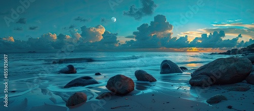 day and night time change concept above huge stones on the sandy beach at twilight. wonderful velvet season vacation. clouds on the blue sky with sun and moon above horizon