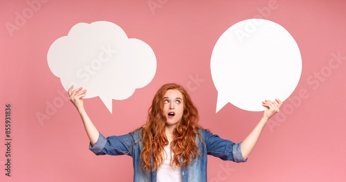 A woman is standing and holding two speech bubbles in front of her face. She appears to be engaged in a conversation or making a public statement, with the speech bubbles emphasizing her words photo