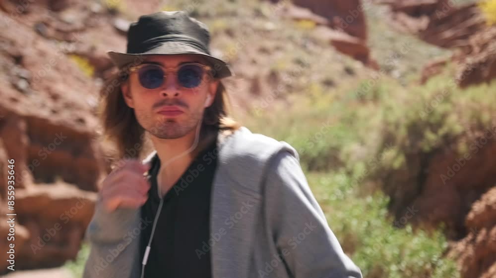slow motion of a handsome young man in sunglasses, hipster hat and cloak dancing close-up among picturesque sandy mountains beautiful nature slow motion of a handsome young man in sunglasses, hipster hat and cloak dancing close-up among picturesque sandy mountains beautiful nature