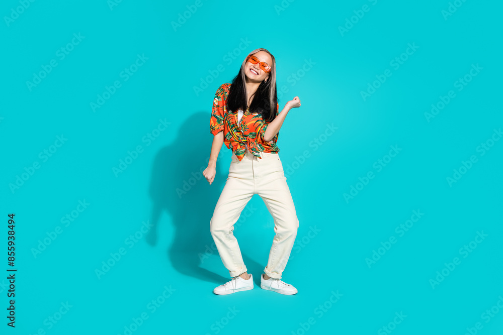Full length photo of cheerful pretty lady dressed orange shirt dancing empty space isolated blue color background Full length photo of cheerful pretty lady dressed orange shirt dancing empty space isolated blue color background