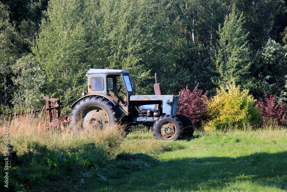 Old blue Russian agricultural tractors in the field. Agricultural machinery in the farm. Forest background Old blue Russian agricultural tractors in the field. Agricultural machinery in the farm. Forest background