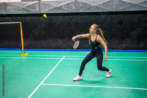 Sports young woman with racket and shuttlecock is exercising, playing in badminton on inside court
