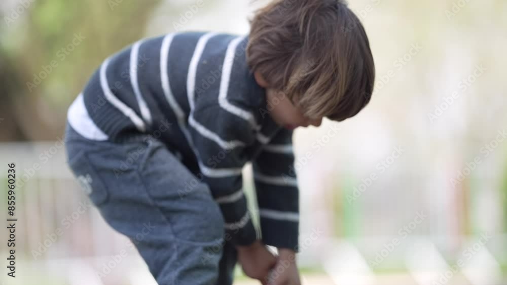 Child Struggles To Lift Overloaded Shovel Of Sand In Outdoor Playground Wearing Striped Sweatshirt During Day Child Struggles To Lift Overloaded Shovel Of Sand In Outdoor Playground Wearing Striped Sweatshirt During Day
