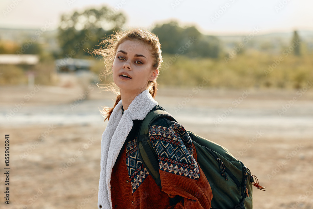 Fototapeta premium Serene woman with backpack in vast empty field at sunset