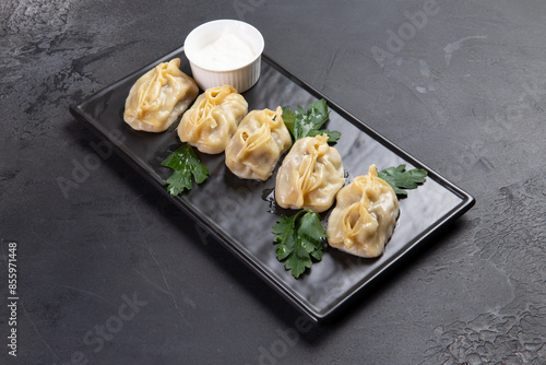 Fototapeta Naklejka Na Ścianę i Meble -  Traditional dish manti on a board. On a dark background.