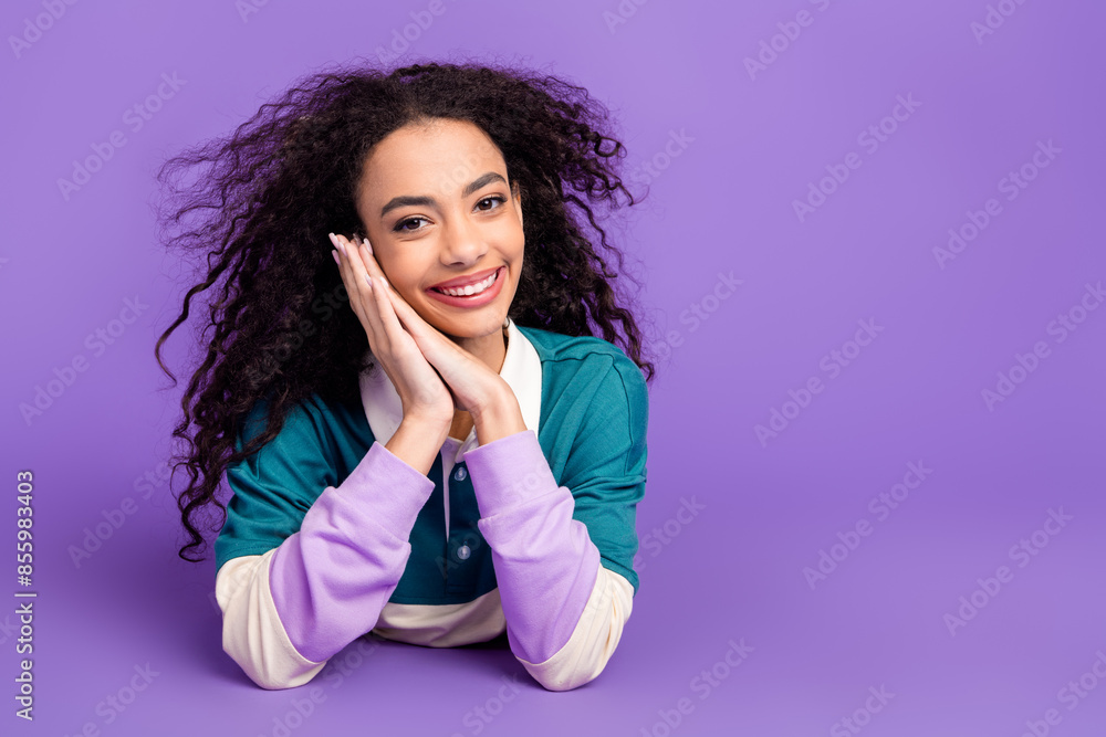 Portrait of lovely young girl lay floor hands under cheek wear shirt isolated on purple color background Portrait of lovely young girl lay floor hands under cheek wear shirt isolated on purple color background