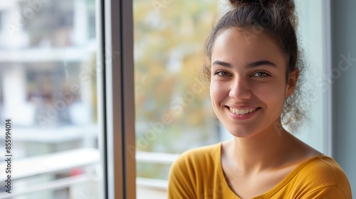 A cheerful young woman in a yellow top with a bright, sunny room in the background Free Download A cheerful young woman in a yellow top with a bright, sunny room in the background - GFXLoad