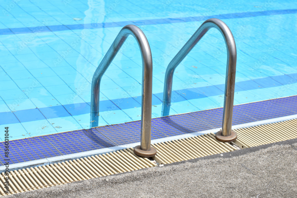 Closeup of Stainless Steel Handrail or Grab bars ladder in the clear blue swimming pool, Concept for convenience in entering the swimming pool at Thailand. Closeup of Stainless Steel Handrail or Grab bars ladder in the clear blue swimming pool, Concept for convenience in entering the swimming pool at Thailand.