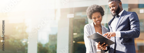 Fotografie Happy couple of african american business partners working while standing outdoors, discussing new project