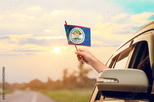 Quadro em tela Waving the Belize flag against the sunrise or sunset from a car driving along a country road