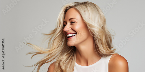 Obraz na płótnie Joyful studio shot of a blonde woman with bleached hair and highlights, laughing and exuding happiness and natural beauty. w salonie