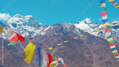 Rack focus shot of Buddhist prayer flags in front of the snowy Himalayan mountain peak at Padum in Zanskar Valley, India. Focus changes from prayer flag to the mountain in back. Natural background.