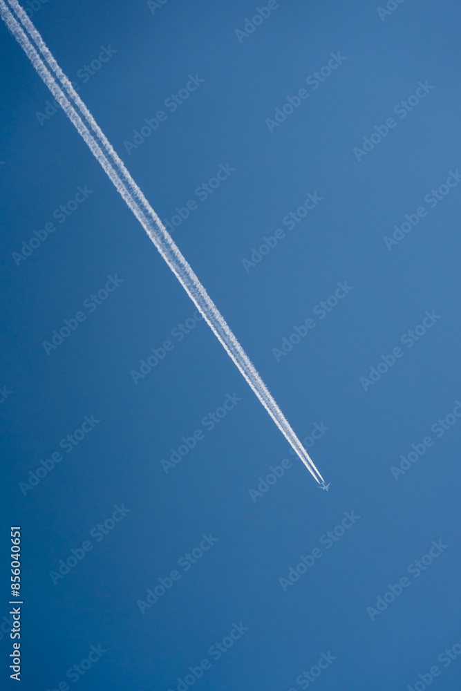 An airplane flying high in the clear blue sky leaves a distinct contrail behind, symbolizing freedom and travel against a simple, minimalist backdrop. An airplane flying high in the clear blue sky leaves a distinct contrail behind, symbolizing freedom and travel against a simple, minimalist backdrop.
