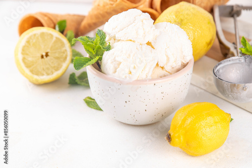 Sour sweet lemon sorbet ice cream, refreshing tasty lemon gelato dessert with fresh lemons, mint and waffle ice cream cones, white table background copy space