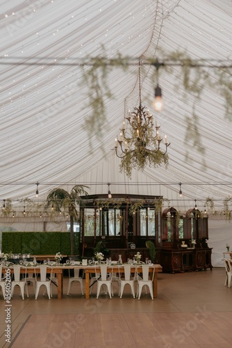 Eegant wedding reception setup in a marquee tent with chandeliers and greenery decor photo